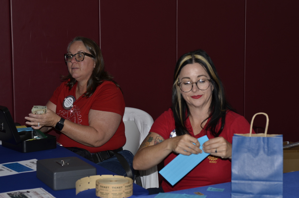 Rotarians and friends smiling behind the gift-basket table at Cherry Jubilee