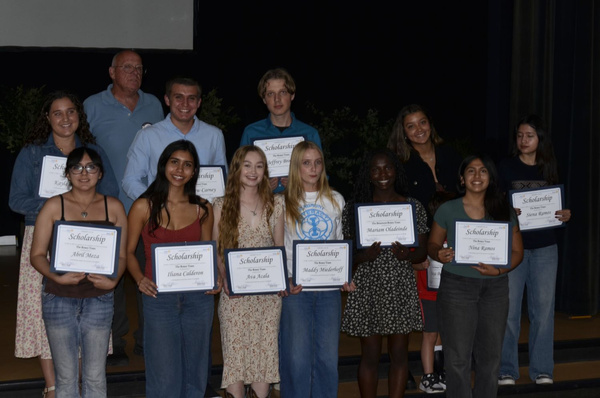Scholarship recipients holding their certificates on stage at Cherry Jubilee
