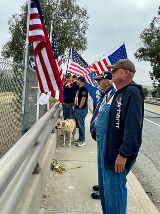 Rotarians on the Singleton Overpass holding American flags as motorcyclists pass below