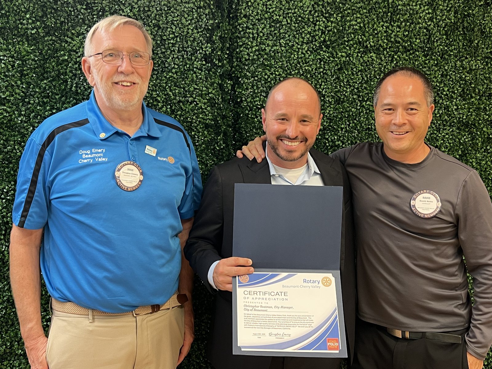 President Doug Emery and club secretary David Heiss stand with City Manager Chris Boatman, who holds an open folder containing his Certificate of Appreciation