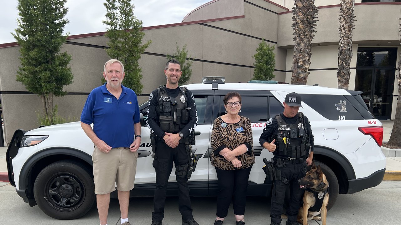 President Doug Emery and Della Condon stand with two Beaumont Police corporals and a police dog in front of a Beaumont PD K-9 unit SUV