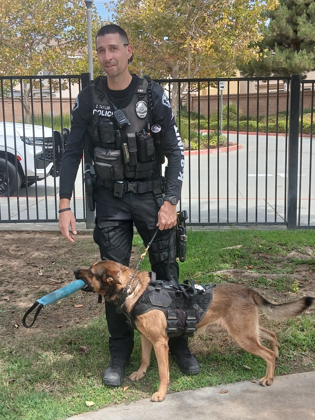 Corporal Taylor of the Beaumont Police Department stands on the grass beside his K9 partner, who is carrying a teal canvas tug toy