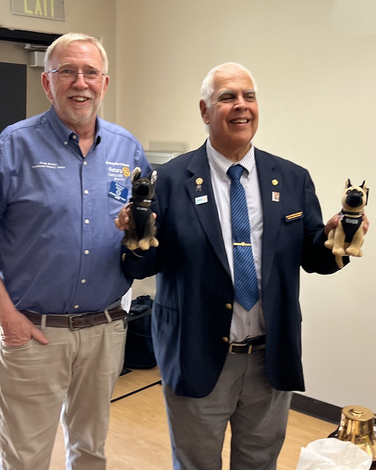 Doug Emery and Richard Lemire laughing, each holding a plush police dog